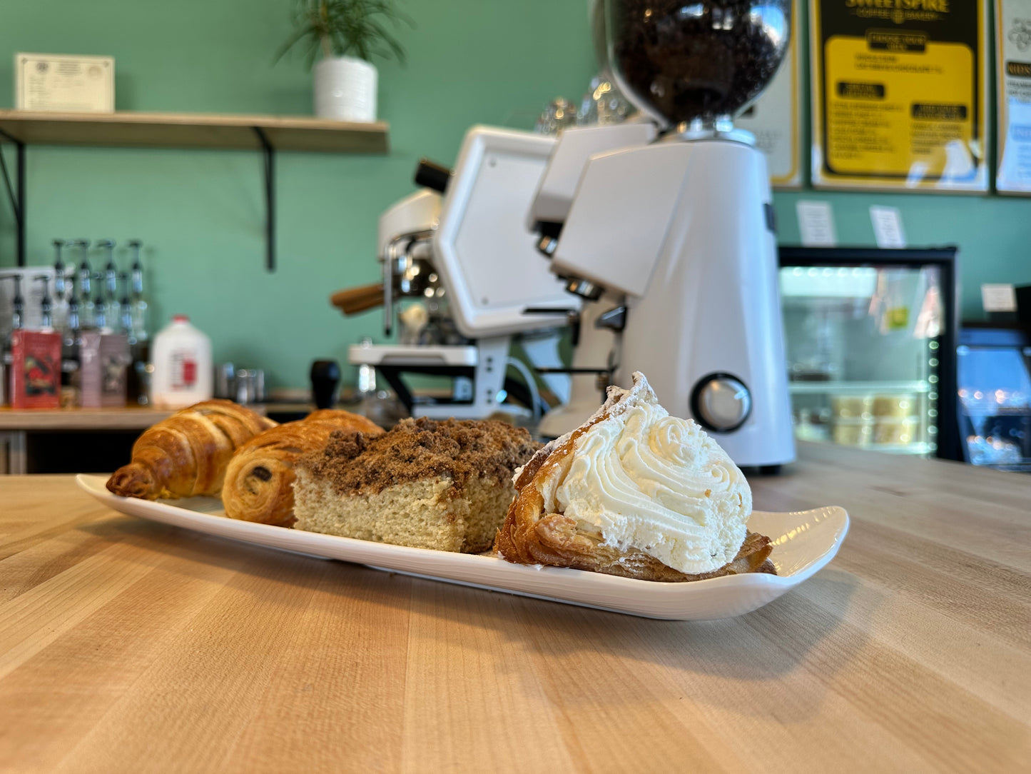 Assorted pastries on a plate with a coffee machine in the background