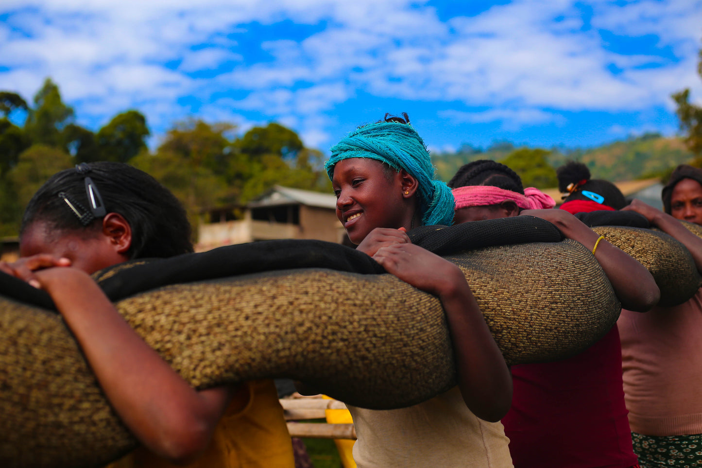4 women carrying a net of raw, washed process coffee over their shoulders