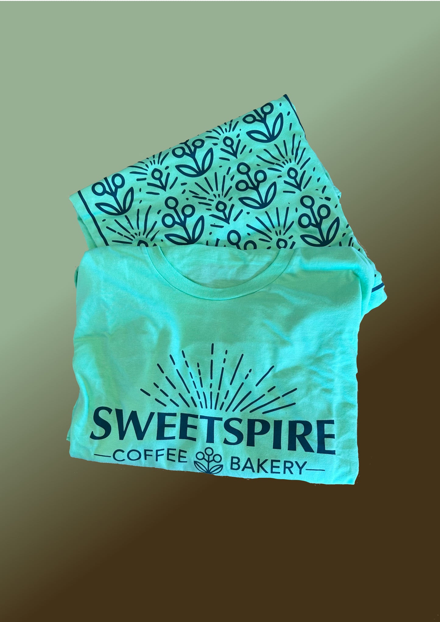 Two green crop tops with 'Sweetspire Coffee Bakery' branding on the front and a flower pattern on the back against a gradient background